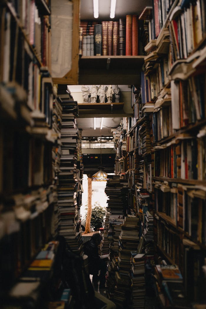 A densely packed library aisle with numerous stacks of books creating a warm and inviting atmosphere.